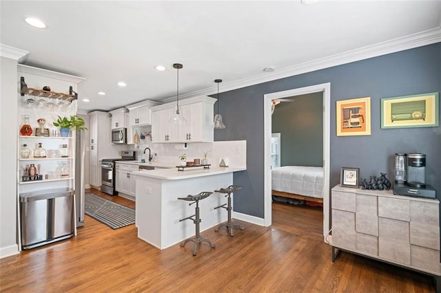 kitchen with decorative light fixtures, white cabinetry, a kitchen bar, kitchen peninsula, and stainless steel appliances