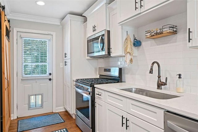 kitchen with white cabinetry, stainless steel appliances, sink, and light stone counters