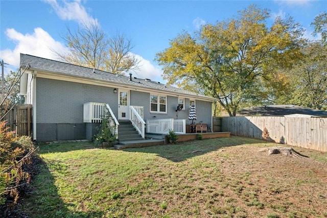 rear view of property with a wooden deck and a yard