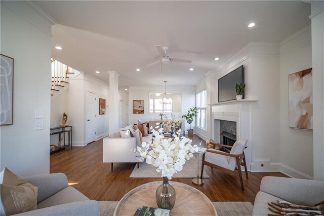 living room with wood-type flooring, ornamental molding, and a high end fireplace