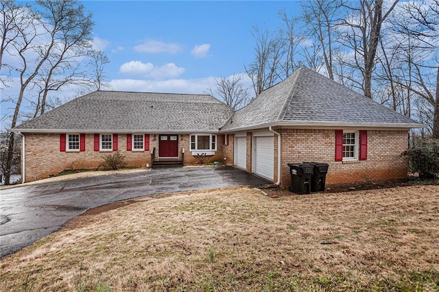 ranch-style house featuring brick siding, an attached garage, a shingled roof, a front lawn, and driveway