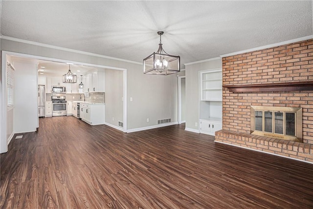 unfurnished living room with a brick fireplace, a textured ceiling, and an inviting chandelier