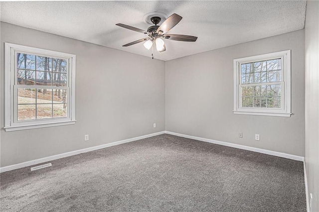 empty room featuring visible vents, a healthy amount of sunlight, a ceiling fan, and carpet