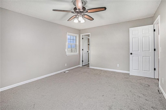 carpeted empty room with visible vents, a textured ceiling, baseboards, and ceiling fan