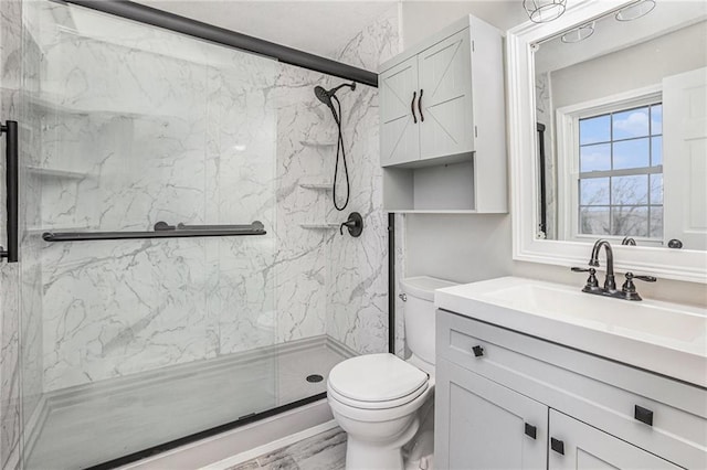 bathroom with vanity, toilet, and a marble finish shower