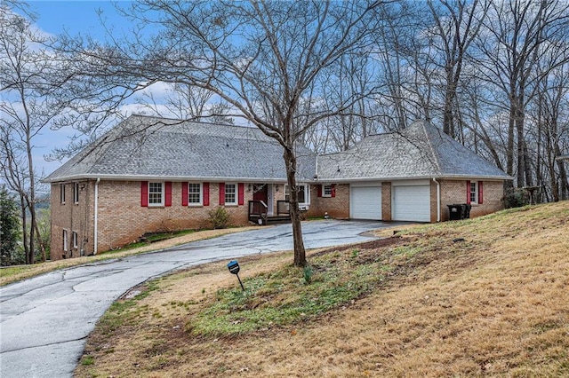 single story home with a garage, a front lawn, brick siding, and driveway