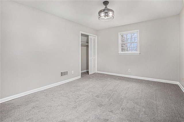 unfurnished bedroom featuring visible vents, baseboards, carpet floors, and a closet