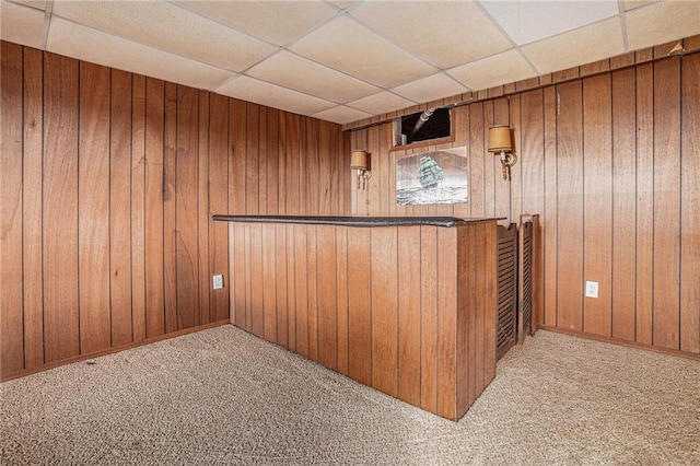 bar featuring carpet, wood walls, and a paneled ceiling