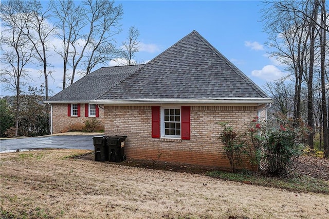 view of home's exterior featuring brick siding and roof with shingles