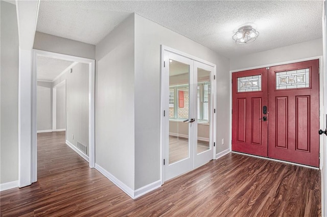 foyer with dark wood-type flooring, french doors, visible vents, and baseboards