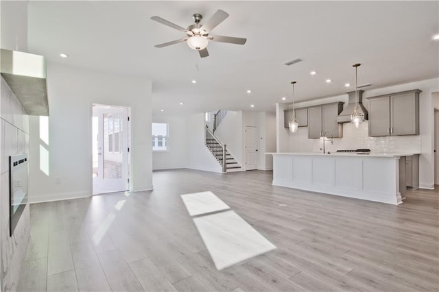 4212 Adler Cir, Buford, GA 30519 - unfurnished living room featuring light wood finished floors, ceiling fan, recessed lighting, stairway, and a sink
