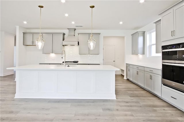 4212 Adler Cir, Buford, GA 30519 - kitchen with double oven, an island with sink, gray cabinetry, and custom exhaust hood