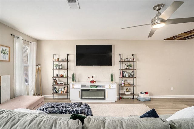 living room featuring ceiling fan and light hardwood / wood-style floors