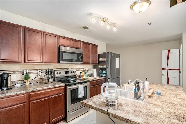 kitchen featuring backsplash, sink, and appliances with stainless steel finishes