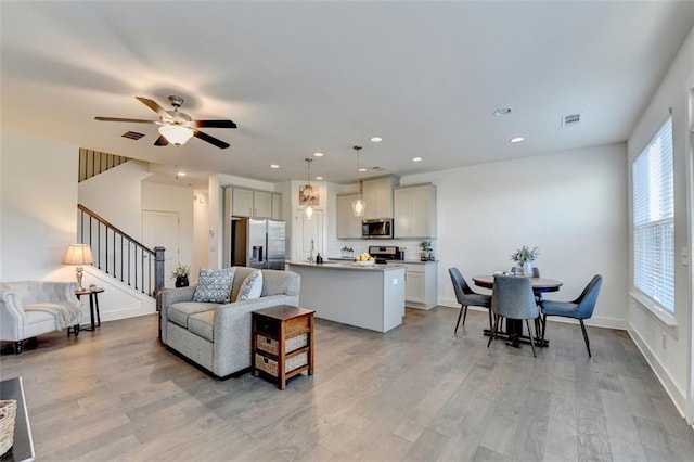 living room featuring a wealth of natural light, ceiling fan, and light wood-type flooring