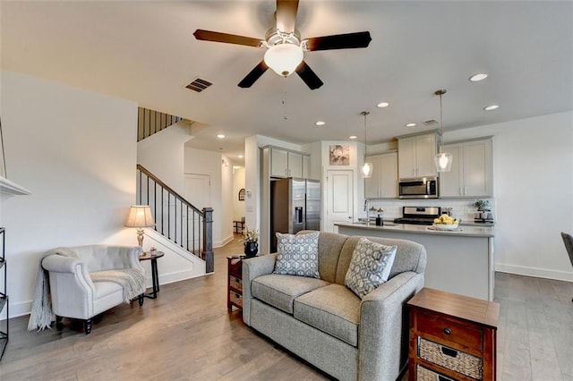 living room featuring ceiling fan, sink, and hardwood / wood-style flooring