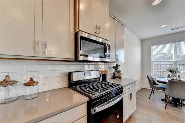 kitchen featuring decorative backsplash, light hardwood / wood-style floors, and appliances with stainless steel finishes