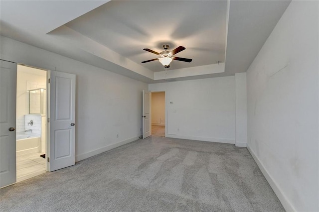 spare room with light carpet, a raised ceiling, and ceiling fan