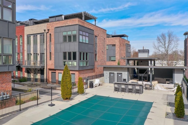 back of property with a patio area, an outdoor bar, fence, and a community pool