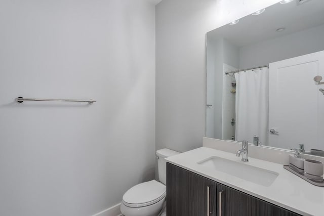 bathroom with curtained shower, baseboards, vanity, and toilet