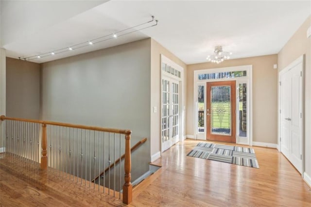 entryway with light wood-type flooring, track lighting, and an inviting chandelier