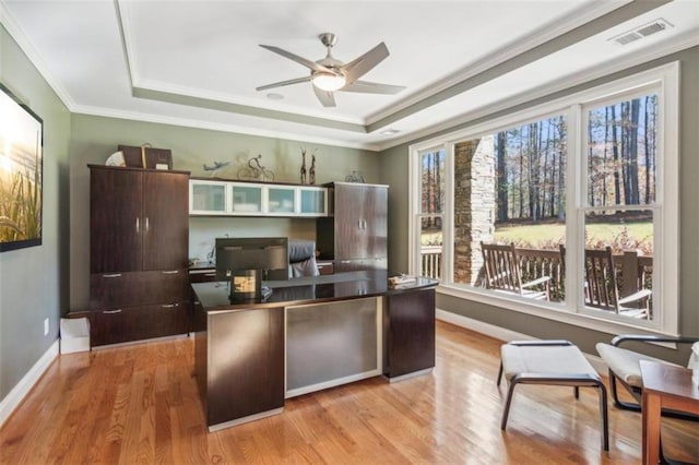 office featuring light wood-type flooring, a tray ceiling, and ornamental molding