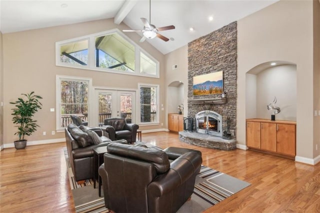 living room with ceiling fan, beamed ceiling, high vaulted ceiling, light hardwood / wood-style floors, and a fireplace