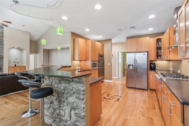 kitchen with hanging light fixtures, light hardwood / wood-style floors, lofted ceiling, a breakfast bar, and appliances with stainless steel finishes