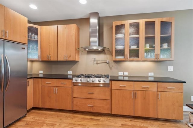 kitchen featuring light wood-type flooring, wall chimney range hood, and stainless steel appliances