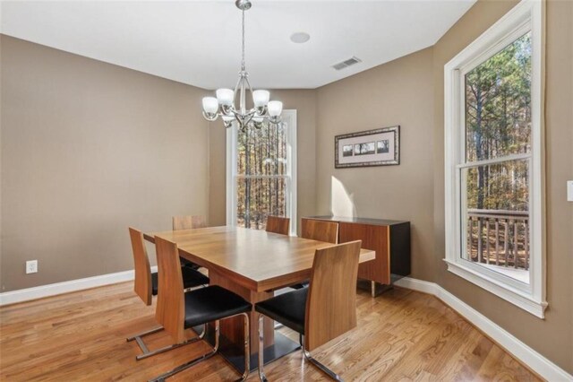 dining room with light hardwood / wood-style floors and an inviting chandelier