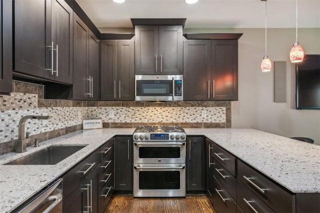 kitchen featuring sink, hanging light fixtures, dark hardwood / wood-style flooring, dark brown cabinets, and appliances with stainless steel finishes