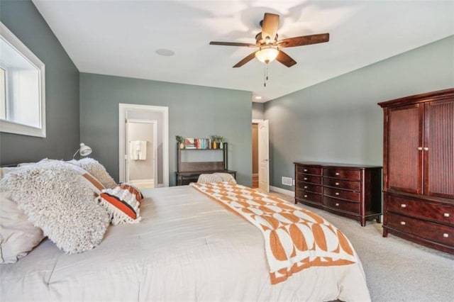 bedroom with ceiling fan, ensuite bathroom, and light carpet