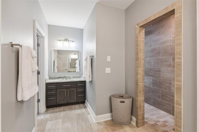 bathroom with a tile shower and vanity