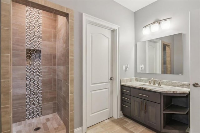 bathroom featuring tiled shower, vanity, and tile patterned flooring