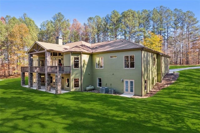 rear view of house with a lawn, french doors, central AC, a wooden deck, and a patio area