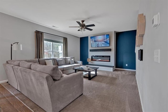 living room with visible vents, baseboards, ceiling fan, carpet flooring, and a glass covered fireplace