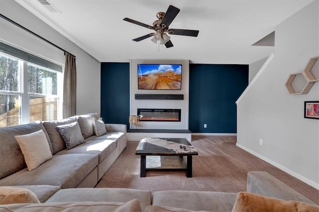 living area featuring visible vents, a glass covered fireplace, carpet flooring, baseboards, and ceiling fan