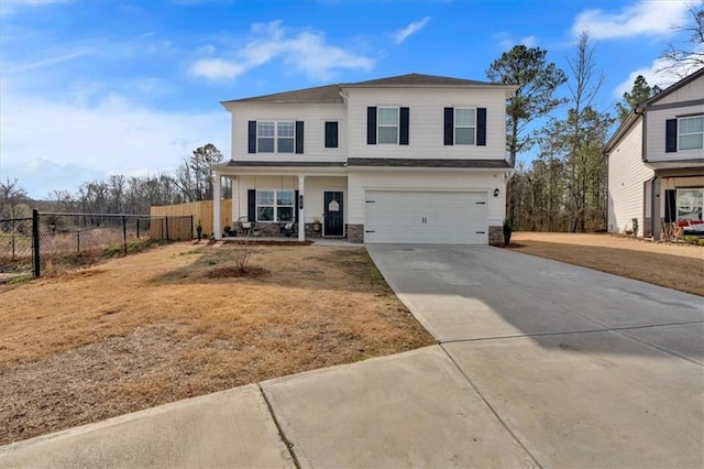 traditional-style home with a front lawn, concrete driveway, an attached garage, and fence