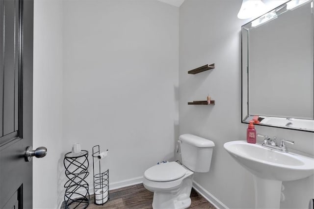 bathroom featuring a sink, baseboards, toilet, and wood finished floors