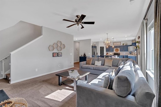 living room featuring ceiling fan with notable chandelier, recessed lighting, carpet flooring, baseboards, and stairs