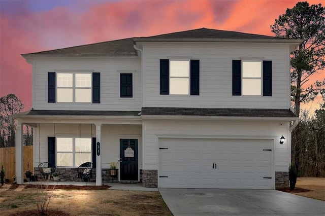 view of front of house with stone siding, covered porch, concrete driveway, and a garage