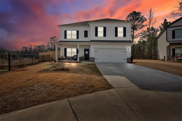 traditional home with fence, driveway, an attached garage, covered porch, and stone siding