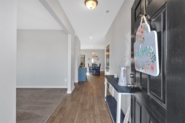 hallway featuring an inviting chandelier, baseboards, and wood finished floors