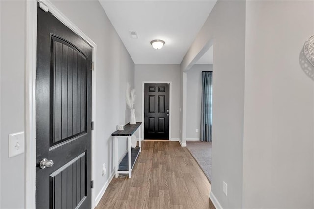 foyer entrance featuring visible vents, baseboards, and wood finished floors