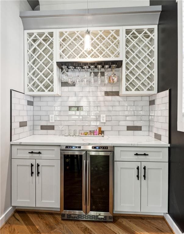 bar with backsplash, beverage cooler, and white cabinets