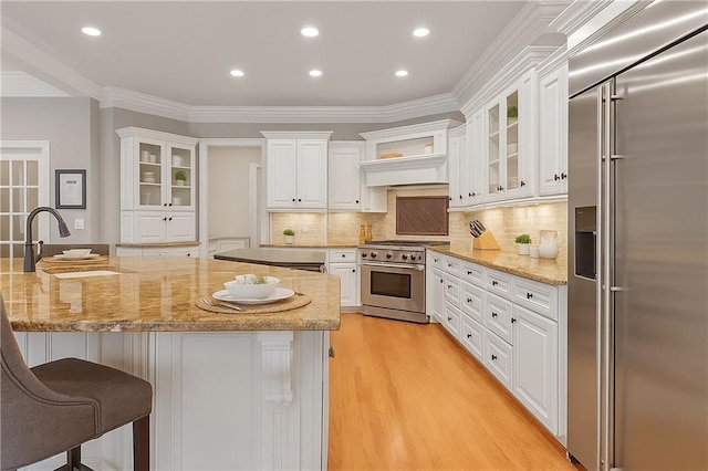 5040 Harrington Rd, Johns Creek, GA 30022 - kitchen with premium appliances, a sink, a breakfast bar area, white cabinets, and ornamental molding