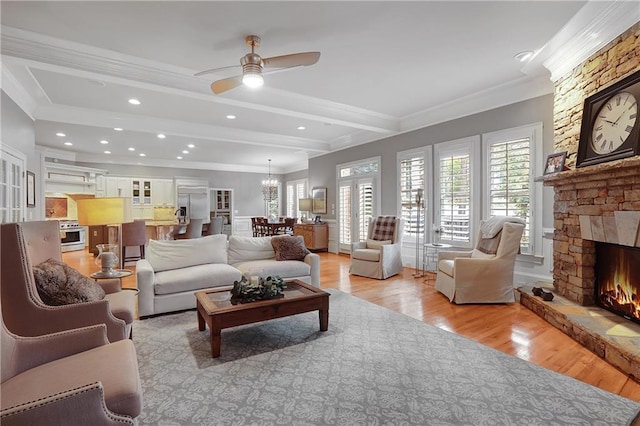 5040 Harrington Rd, Johns Creek, GA 30022 - living area featuring crown molding, light wood-type flooring, a stone fireplace, a ceiling fan, and a chandelier
