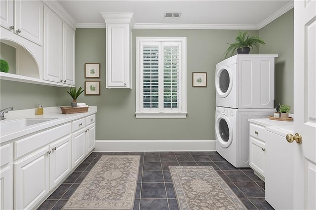 5040 Harrington Rd, Johns Creek, GA 30022 - laundry area featuring stacked washing machine and dryer, ornamental molding, cabinet space, baseboards, and dark tile patterned flooring