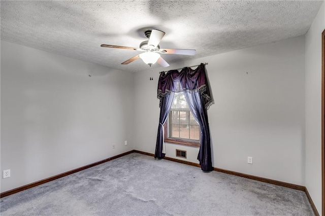 empty room featuring ceiling fan, light carpet, and a textured ceiling