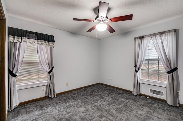 unfurnished room featuring ceiling fan, dark carpet, and a textured ceiling